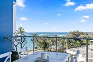 a balcony with a table and a view of the ocean at Oceanfront Spa Suite - Sub Penthouse in Urangan