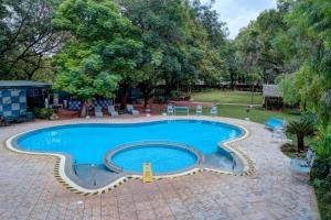 a large swimming pool in a yard with trees at Hotel Tamilnadu Pandiyan Madurai in Madurai
