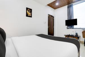 a bedroom with a white bed and a television at Collection O De Alphabet Hotel in Hyderabad