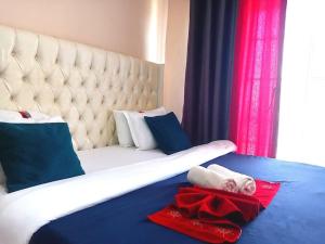 a bedroom with a bed with a white headboard and a red towel at New Dawn luxury homes in Nairobi