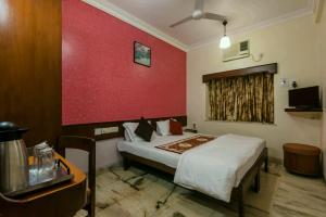 una camera con letto e parete rossa di Hotel Mogul Palace - Near CST Station a Mumbai