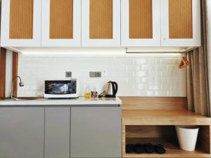 a kitchen with white cabinets and a microwave on a counter at R7 Cottages Pangandaran in Cikembulan