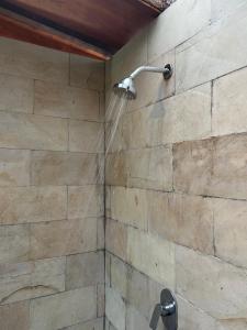 a shower with a shower head on a stone wall at Kelapa Sunrise Villa in Silebeng +3 photos