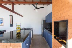 a kitchen with blue cabinets and a ceiling fan at QUINTAL DE BÚZIOS- casa com piscina e 3 suítes completas in Búzios