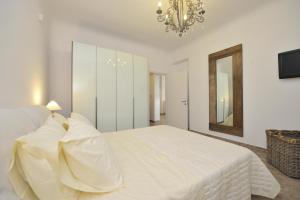 a white bedroom with a large bed and a chandelier at Chrysalis Nature Villa 3 in Kampos Paros +68 photos