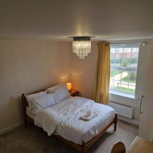 a bedroom with a bed with a chandelier and a window at Nairn Way House in Kirby Muxloe