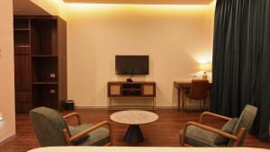 a living room with a tv and chairs and a table at Aanya Taara Resort- Mettupalayam in Mettuppālaiyam