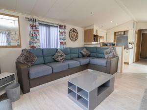 a living room with a blue couch and a kitchen at Caravan CP10 in Prestatyn