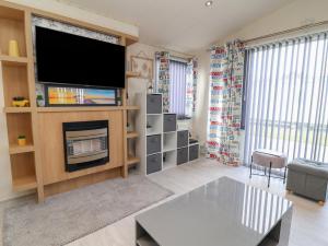 a living room with a flat screen tv and a fireplace at Caravan CP10 in Prestatyn