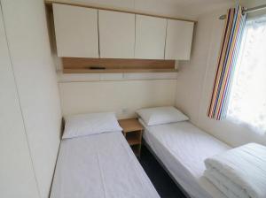 two beds in a small room with a window at Caravan CP10 in Prestatyn