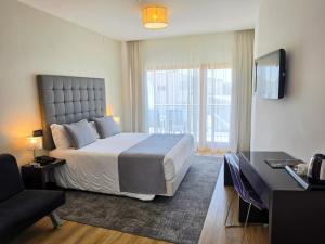 a bedroom with a bed and a desk and a television at Hotel Miramar Sul in Nazaré