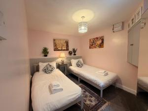 a room with two beds and a table and a lamp at Lorash Cottage, Ashbourne in Ashbourne