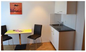 eine kleine Küche mit einem Tisch, Stühlen und einem Waschbecken in der Unterkunft Hotel Garni Bären Bazenheid in Bazenheid