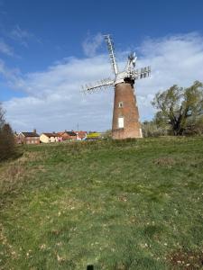 a windmill on top of a grassy field at The BILLINGFORD HORSESHOES in Scole