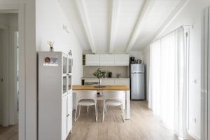 a white kitchen with a wooden table and white appliances at Maison Bellini number 3 in Toscolano Maderno
