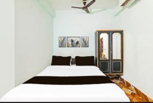 a bedroom with a white bed with a ceiling fan at Hotel welcome inn in Patna