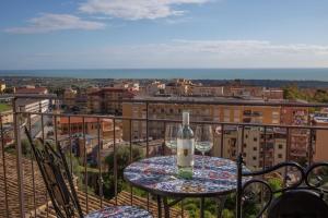 a table with a bottle and glasses on a balcony at B&B Sikelia Suite in Agrigento
