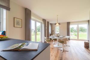 a kitchen and living room with a table and chairs at Haus an der Koppel in Borgsum