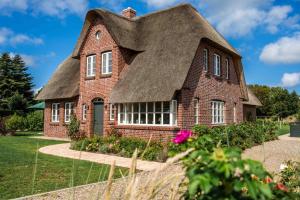 an old brick house with a thatched roof at Haus an der Koppel in Borgsum