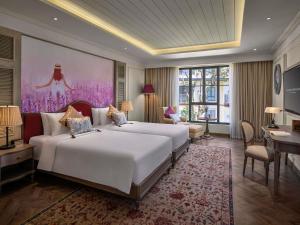 a bedroom with a large white bed and a desk at Grand Mercure Dalat in Da Lat +201 photos