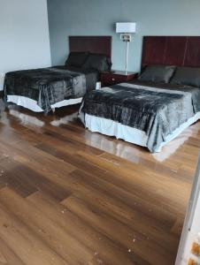 two beds in a room with wooden floors at Maplehurst Motel in Tunkhannock