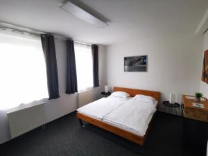 a bedroom with a bed with white sheets and two windows at Pilotenunterkunft Fliegerhorst in Strausberg