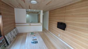 a room with wood paneling and a television on a wall at お宿&カフェバーもか in Higashikagawa