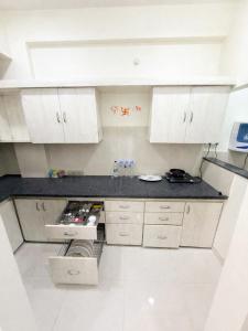 a kitchen with white cabinets and a black counter top at LaBelle Haven Aesthetic Cozy 2BHK For Family and Couples in Indore