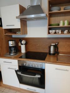 a stove top oven in a kitchen with white cabinets at Ferienwohnung May in Seiwerath +8 photos