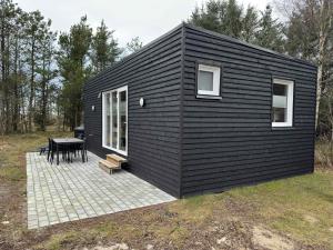 a black house with a picnic table and a patio at Rødhus Camping in Pandrup
