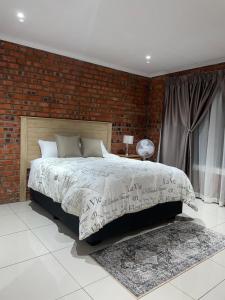 a bedroom with a bed and a brick wall at Kubbe Comfort Corner in Bloemfontein
