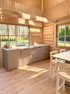 a kitchen in a log cabin with a table and chairs at Liedaga 24 in Tūja