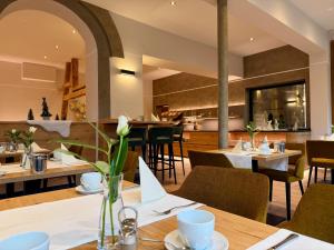 a restaurant with tables and chairs and a kitchen at Hotel Donaublick in Scheer