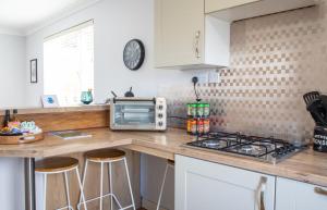 a kitchen with white cabinets and a counter top with stools at Skeabost View Chalet in Portree +29 photos