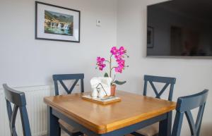 a wooden table with a vase with a flower on it at Skeabost View Chalet in Portree