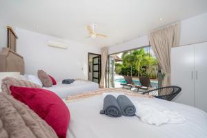 two beds in a bedroom with a view of a pool at Nivara Pool Villa - Rawai in Rawai Beach