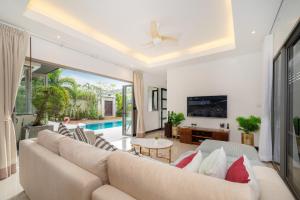 a living room with a couch and a tv at Nivara Pool Villa - Rawai in Rawai Beach