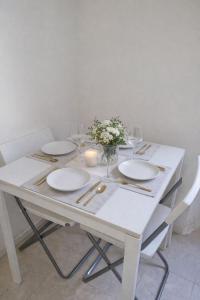 a white table with plates and glasses and a candle at Appartamento Duomo-Monte Nero in Milan