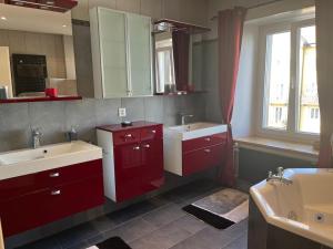 a bathroom with red cabinets and two sinks and a window at Charming Apartment with Jacuzzi Bathtub in La Chaux-de-Fonds +10 photos
