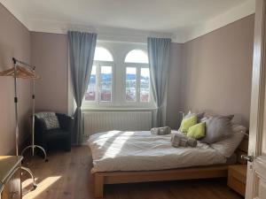a bedroom with a bed and two windows and a chair at Charming Apartment with Jacuzzi Bathtub in La Chaux-de-Fonds