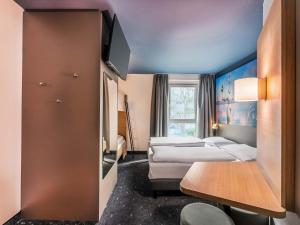 a hotel room with two beds and a tv at B&B Hotel Konstanz in Konstanz