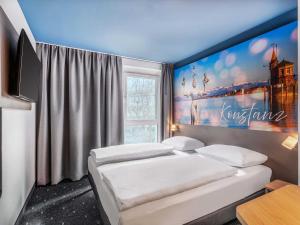 a room with two beds and a large painting on the wall at B&B Hotel Konstanz in Konstanz