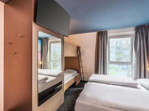 a hotel room with two beds and a mirror at B&B Hotel Konstanz in Konstanz