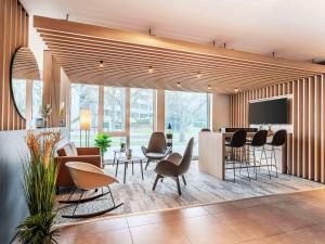 a living room with chairs and a bar with a tv at B&B Hotel Konstanz in Konstanz +19 photos