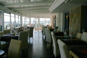 a dining room with tables and chairs and windows at Hotel Le Suroit in Perros-Guirec