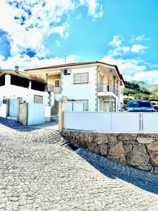 a house with a white fence and a stone wall at Casa Encosta do Marao in Amarante