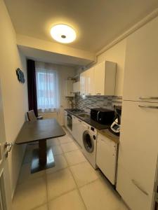 a kitchen with a table and a washer and dryer at Apartament cu 2 camere decomandate in Roşu +6 photos