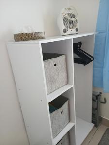 a white book shelf with boxes and a fan at Seashells-L10 in Dawlish Warren