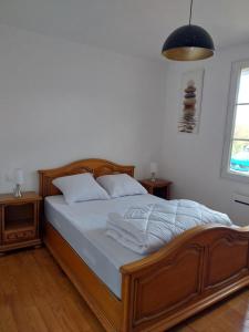 a bedroom with a wooden bed with white sheets at Le Dom'Mino in Condé-Folie
