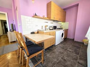 a kitchen with purple walls and a wooden table with chairs at Apartman Gloria Sajam - Senjačka pijaca in Senjak (historical)